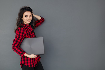 Wall Mural - caucasian smiling student girl holding laptop over gray background