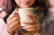 © sbw19 - Close up of woman hands holding a cup of coffee. Female in winter fashion clothes enjoying hot drink with smiling face,selective focused.