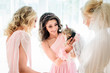 Bride and bridesmaids in pink dresses play with little fluffy do