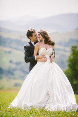 Wall Mural - Happy groom hugs bride tender from behind standing with her on h