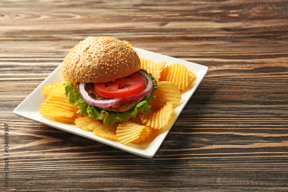 Tasty burger with potato chips on plate