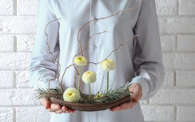 Poster - Woman holding floral composition on brick wall background