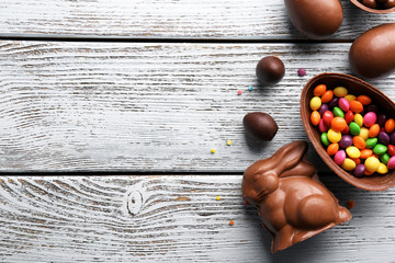 Wall Mural - Chocolate Easter eggs, rabbit and sweets on light wooden background