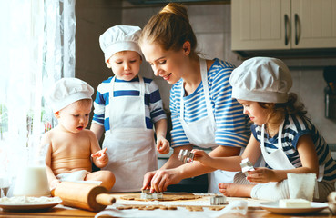 Wall Mural - happy family in kitchen. mother and children preparing dough, ba