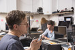 © Mint Images - Three people working in a technology lab, with a man in the foreground looking at a cellphone.