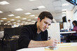 © Mint Images - A man sitting at a table in an office writing.