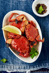 Wall Mural - Red boiled crabs with a lemon and parsley in a plate.On a blue background