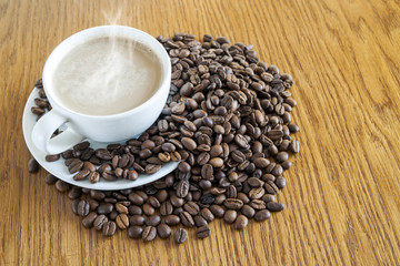 Wall Mural - Cup of coffee in a white cup and coffee beans on wooden table ba