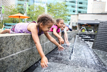 Children Playing In A City Fountain. Shallow Focus On Girls Face