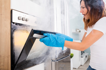 Wall Mural - Woman Opening Door Of Oven Full Of Smoke