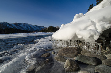 Wall Mural - icicles pose in the spring sun, teket river in the background, the mountains on the horizon.