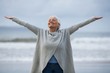 © WavebreakMediaMicro - Senior woman with arms outstretched standing on the beach
