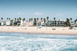 Pacific ocean coastline in Los Angeles USA. People walking at the beach. Rental buildings on Venice beach.
