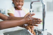 Siblings Washing Hand In Kitchen At Home
