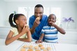 Father and kids eating cookies at home
