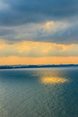 Wall Mural - Beautiful sunrise over the sea in the morning on cloudy day that sun beams break through the clouds. Sun beaming through clouds with urban landscape, if you zoom in will see the small fishing boats.
