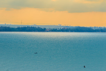 Wall Mural - Beautiful sunrise over the sea in the morning on cloudy day that sun beams break through the clouds. Sun beaming through clouds with urban landscape, if you zoom in will see the small fishing boats.