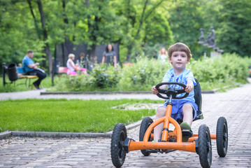 Wall Mural - Little preschool boy driving big toy sports car and having fun, outdoors.