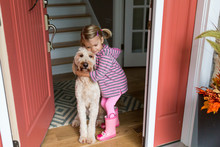 Young Girl And Dog Cuddling At Doorway 