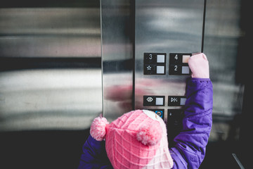 Young girl pressing elevator button 