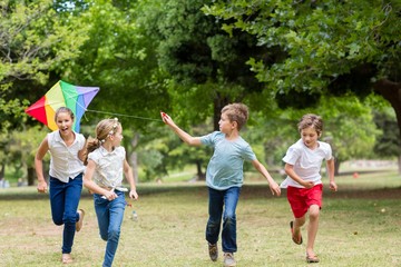 Wall Mural - Kids playing with a kite in park