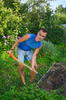 © herculerus - Young smiling man digging a garden bed for planting Apple trees