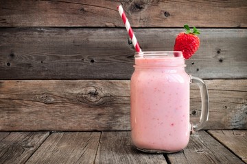 Wall Mural - healthy strawberry smoothie in a mason a jar mug over a rustic wood background