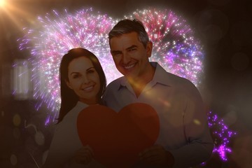 Poster - Composite image of happy couple holding big heart shape paper