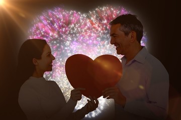 Poster - Composite image of smiling couple holding heart shape paper