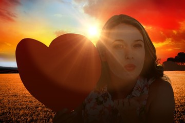 Canvas Print - Composite image of woman holding heart card and blowing kiss