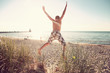 Boy jumping off of  dunes at the beach.