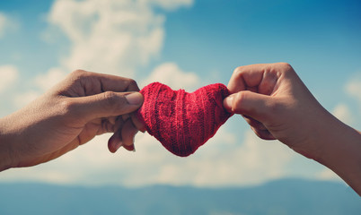 Close up couple hands holding red hearts