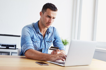 Wall Mural - man holding credit card and using laptop