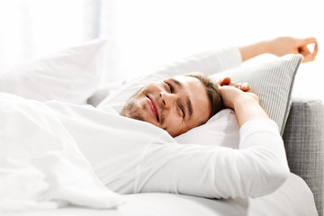 Handsome man stretching in bed