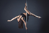 Young slim pole dance girl of asian appearаnce on a black studio background