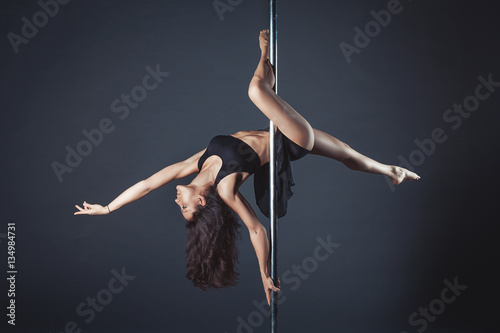 Fotografie, Obraz Young slim pole dance girl of asian appearаnce on a black studio background