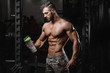 © antondotsenko - Handsome athletic fitness man holding a shaker and posing gym
