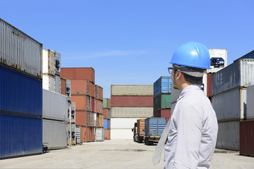 The engineer looking at the container stack at  ship yard with the blue sky