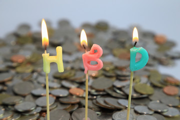 The candle light with text is H B D, color yellow, pink and blue as money or coins background or print card. Happy Birthday and Business Concept for dark tone.