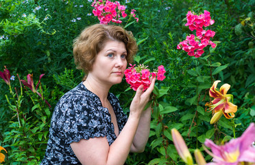 Wall Mural - woman inhales aroma of phlox in garden