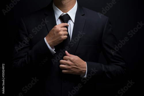 Fotografía Man in black suit and adjusting his necktie