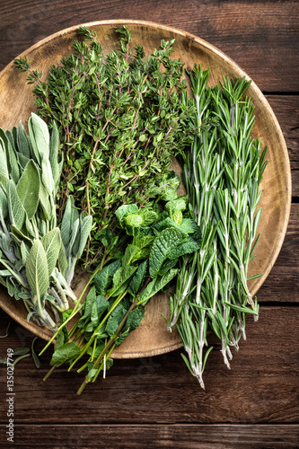 Cuadros en Lienzo Varias hierbas frescas, romero, tomillo, menta y salvia sobre fondo de madera