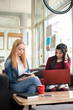 © Bojan - Two female students studying with book and laptop at a cafe.
