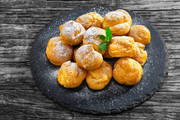 Wall Mural - Delicious profiteroles filled with cream on slate plate