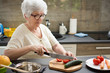 © Bojan - Senior woman preparing healthy food from fresh vegetables in kitchen.