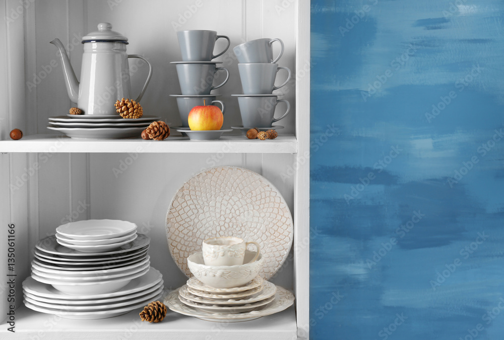 Different clean dishes in cupboard in the kitchen