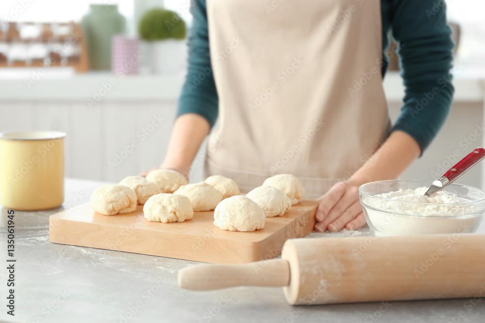 Woman making small balls of dough on table in kitchen