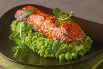 Grilled salmon pea puree decorated with mint on a brown plate. G