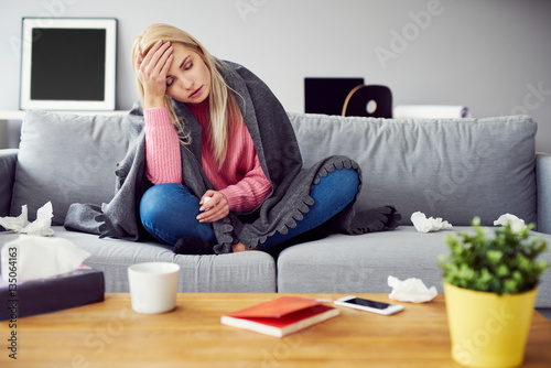 Fotografia Sick woman with headache sitting under the blancket in living ro