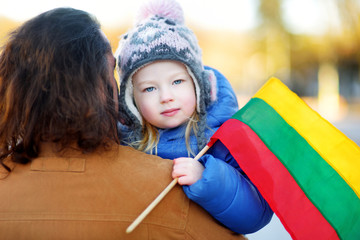 Wall Mural - Father and daughter with a flag on Lithuanian independence day holding tricolor Lithuanian flag